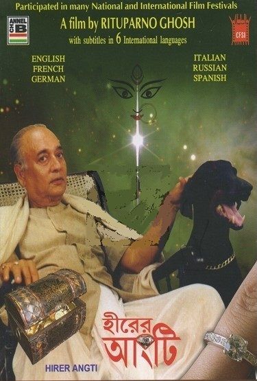 A medium skin toned South Asian adult man sits leisurely in a lounge chair and pets a large black dog with a silver chain on its neck. A chest of treasures is inserted at the bottom left corner near the man's other hand. A closeup of a ring on a finger is imposed on the bottom right corner of the poster. The poster has a green background with a starry sky illusion and there is a drawing of a Hindu figure face above a shining star. Various text is featured on the poster about the film title, director, languages available and festival participation.