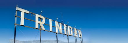 It is a white sign that says "Trinidad '' and a clear blue sky in the background.